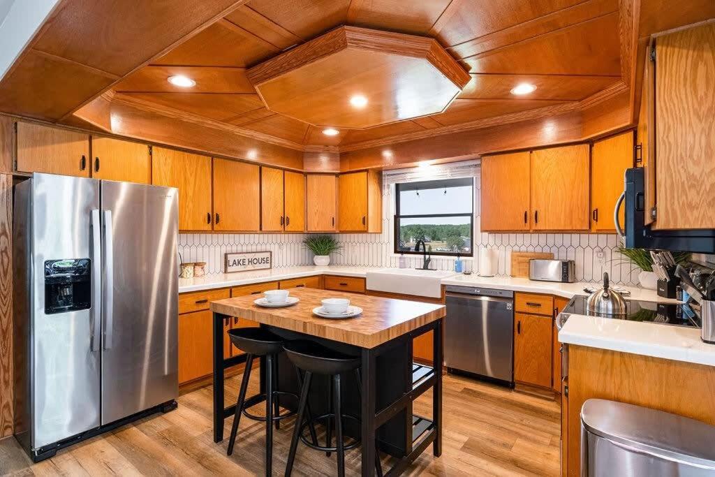a kitchen with a stainless steel refrigerator and wooden cabinets at 5BR Lakefront Getaway with hot tub in Cadillac