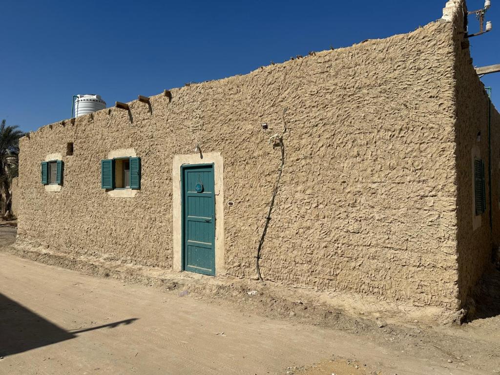 ein Backsteingebäude mit einer blauen Tür und Fenstern in der Unterkunft Thraa - ثراء in Siwa
