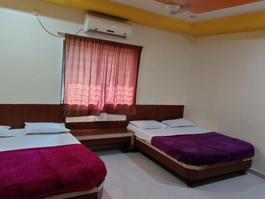 sypialnia z 2 łóżkami i oknem z fioletową pościelą w obiekcie Aditya palace w mieście Shirdi