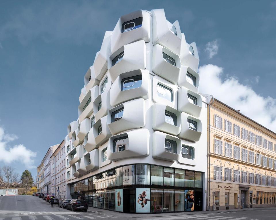un bâtiment blanc avec des fenêtres sur le côté d'une rue dans l'établissement limehome Graz - Argos by Zaha Hadid, à Graz