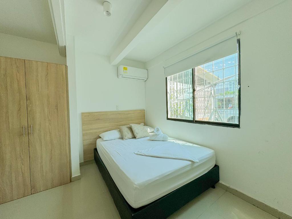 Hotel Tamara House في سانتا مارتا: غرفة نوم صغيرة مع سرير مع نافذة