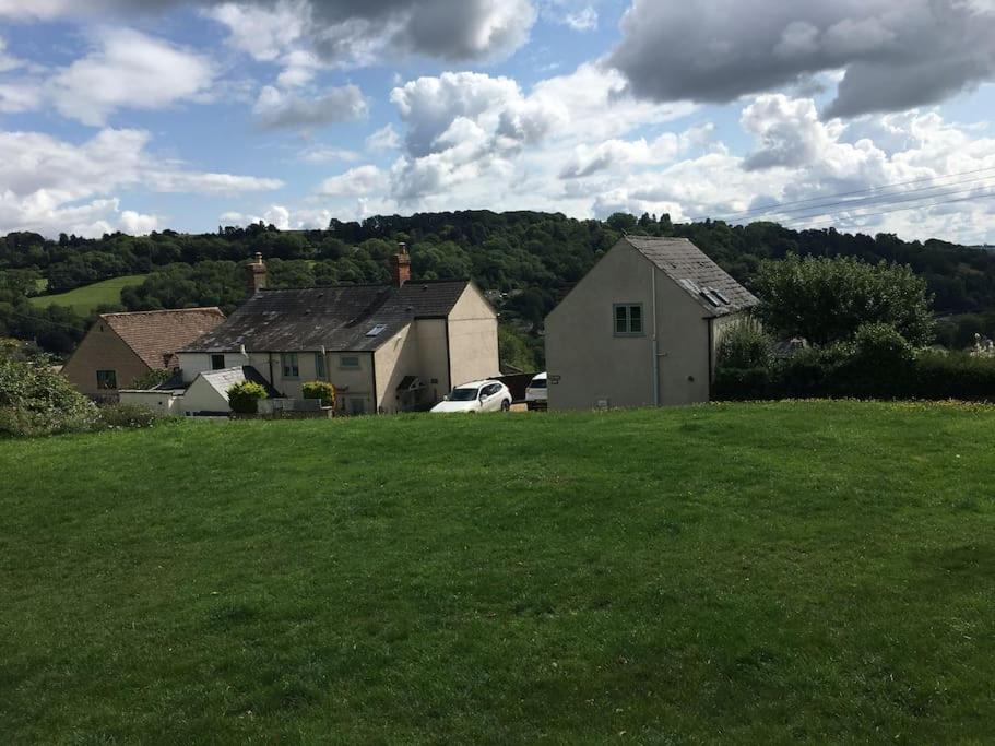 a green field with two houses and a car at The Annex at Kronstad in Stroud
