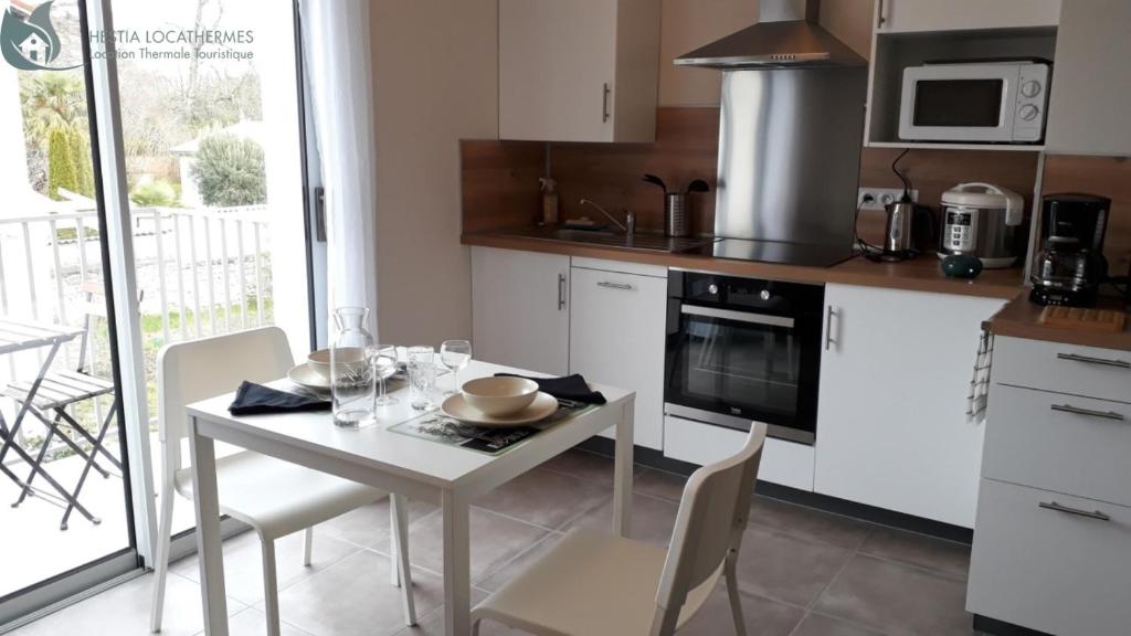 une cuisine avec une table blanche et des chaises dans l'établissement Calme et Central à Jonzac, à Jonzac