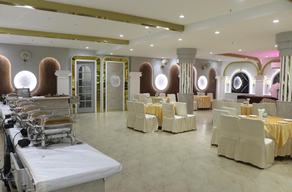 a dining room with white tables and white chairs at Hotel Landmark in Sahāranpur