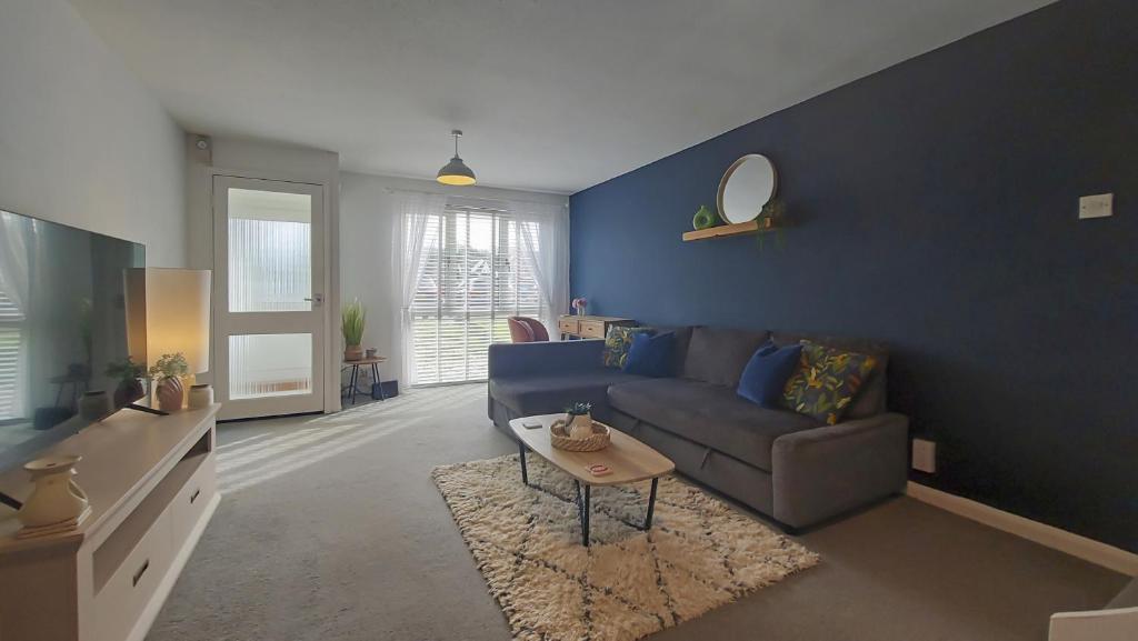 een blauwe woonkamer met een bank en een tafel bij 2BD Home: Locale Near Old Town & Fast London Links in Stevenage