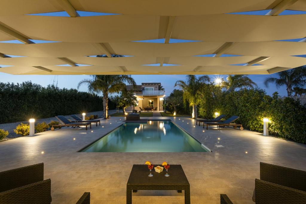 - une piscine avec une terrasse et une maison dans l'établissement Villa Emanuela - IsulaTravel, à Ispica