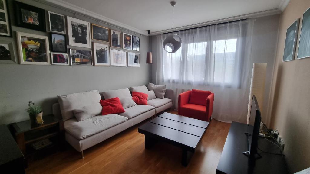 uma sala de estar com um sofá e uma cadeira vermelha em Piso zona hospital 7 personas em Oviedo