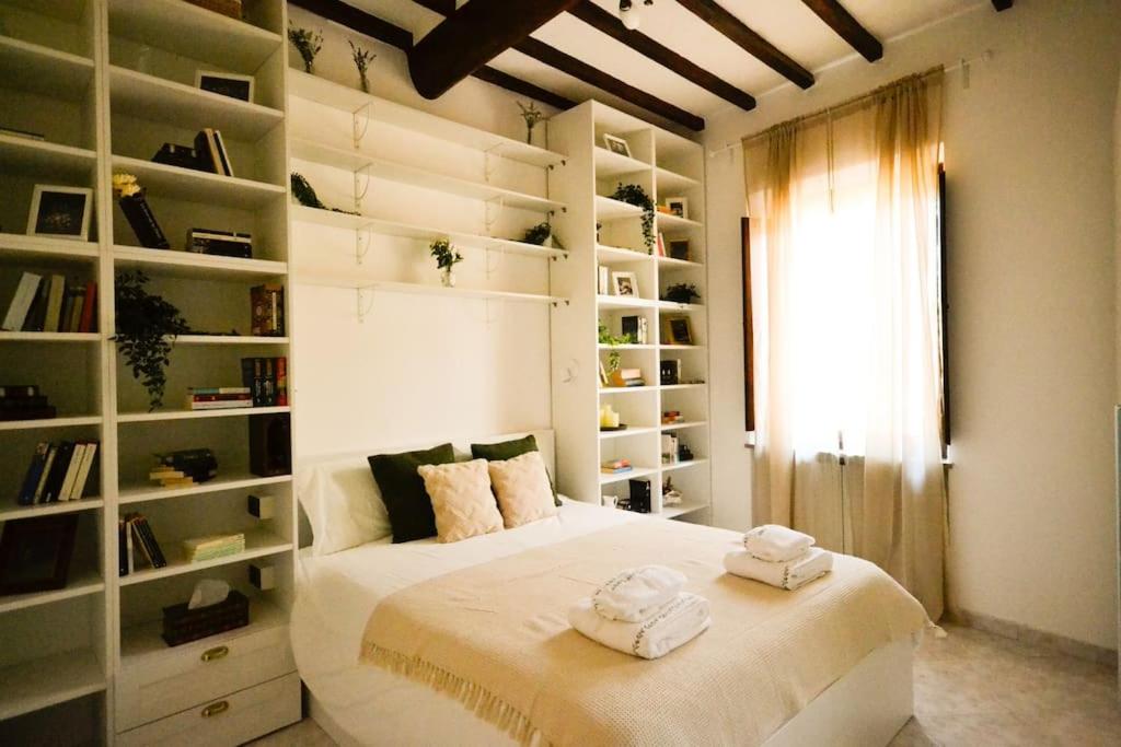 een slaapkamer met een groot wit bed en planken bij The Librarian's home in San Gimignano