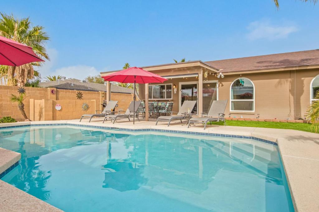 une piscine avec deux parasols et une maison dans l'établissement Teal Gardens - Private Pool - Mins to Kierland, à Phoenix