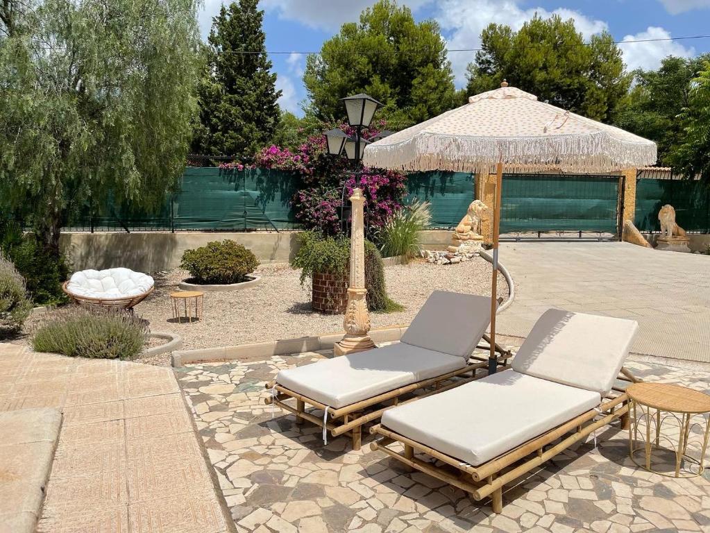 two lounge chairs and an umbrella in a courtyard at Casa San Cayetano in Crevillente