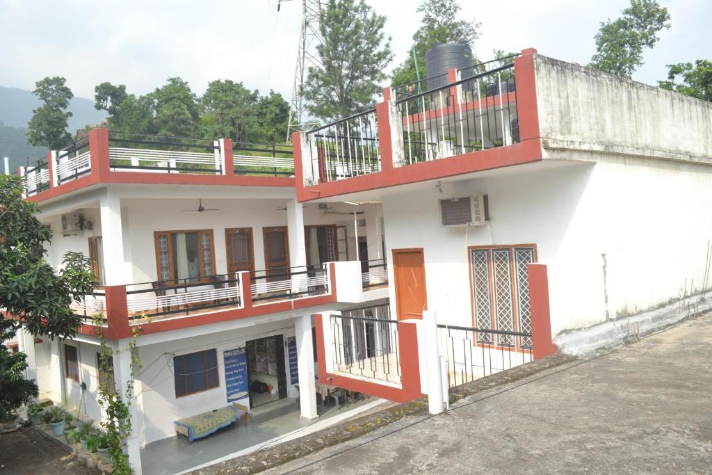 a white and red building with a balcony at Mount Valley Mama Cottage in Rishīkesh