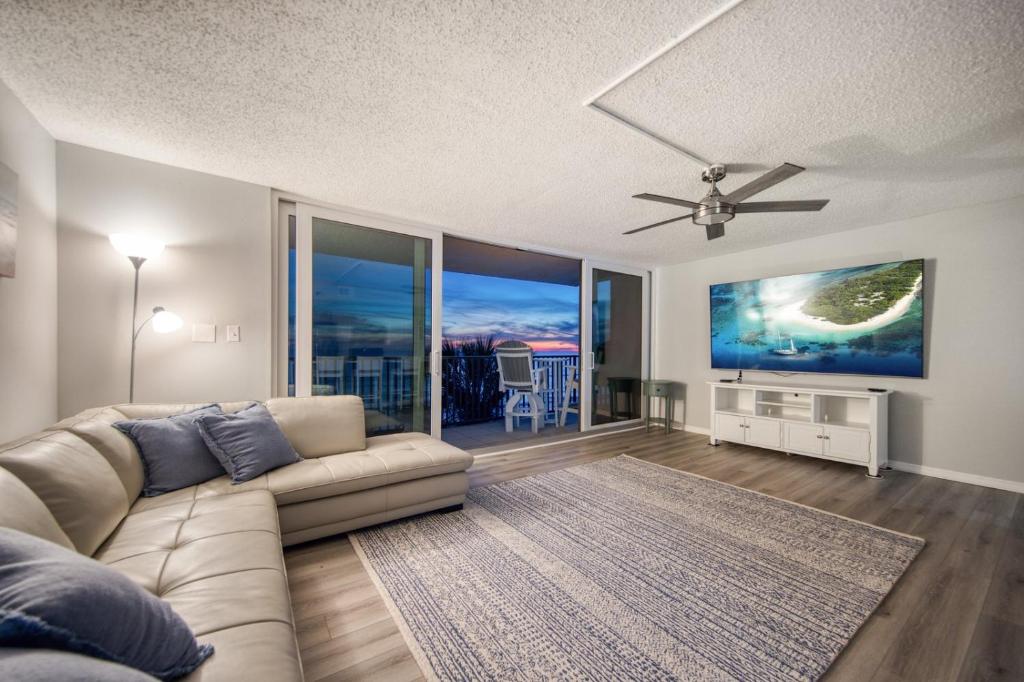 a living room with a couch and a ceiling fan at Huge Beachfront Condo on Maderia Beach in St. Pete Beach