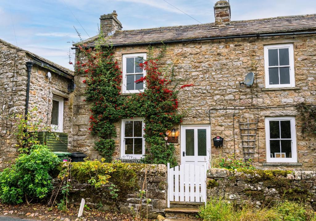 an old stone house with a white fence at Rose Cottage in Richmond