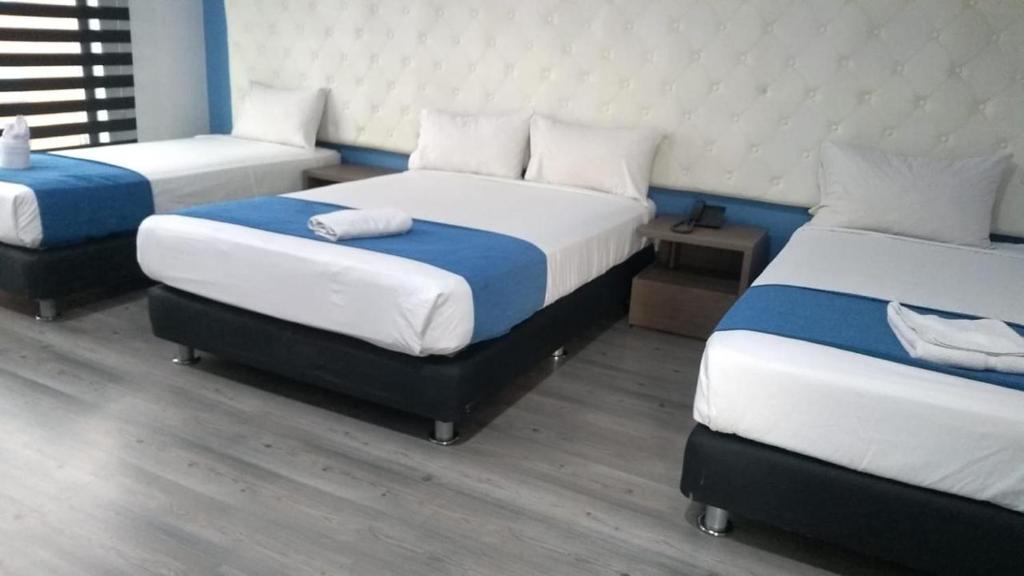 a room with three beds in a room at Plaza Miranda in Bogotá