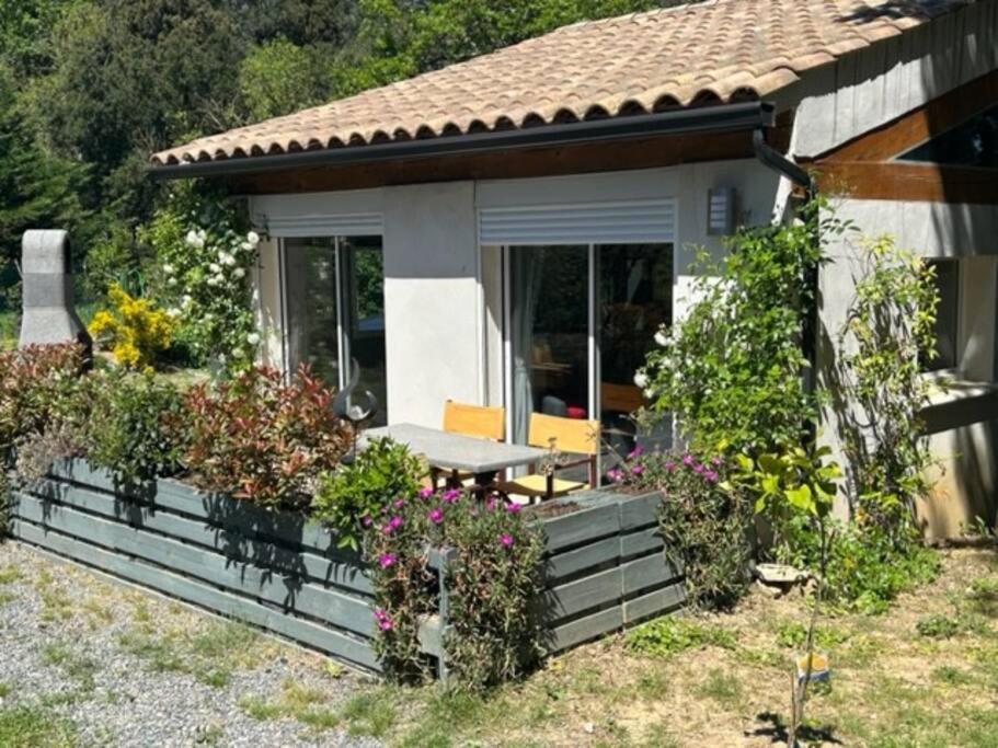 una casa con un porche con flores y plantas en Gite 4/6 pers près du Lac en pleine nature en Carcassonne