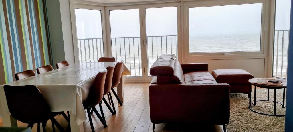 a living room with a table and chairs and the ocean at Zeedijk 241 in Koksijde
