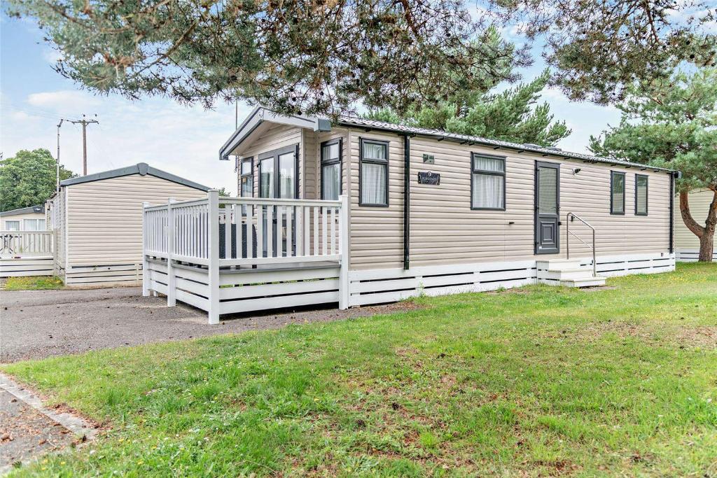a mobile home with a porch and a yard at 2 Bed 6 Berth Lodge in Shorefield Oakdene Dorset in Ferndown