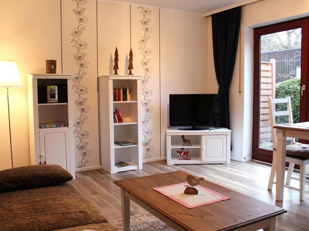 Una sala de estar con un televisor y una mesa. en Apartment Florentine, en Bad Harzburg
