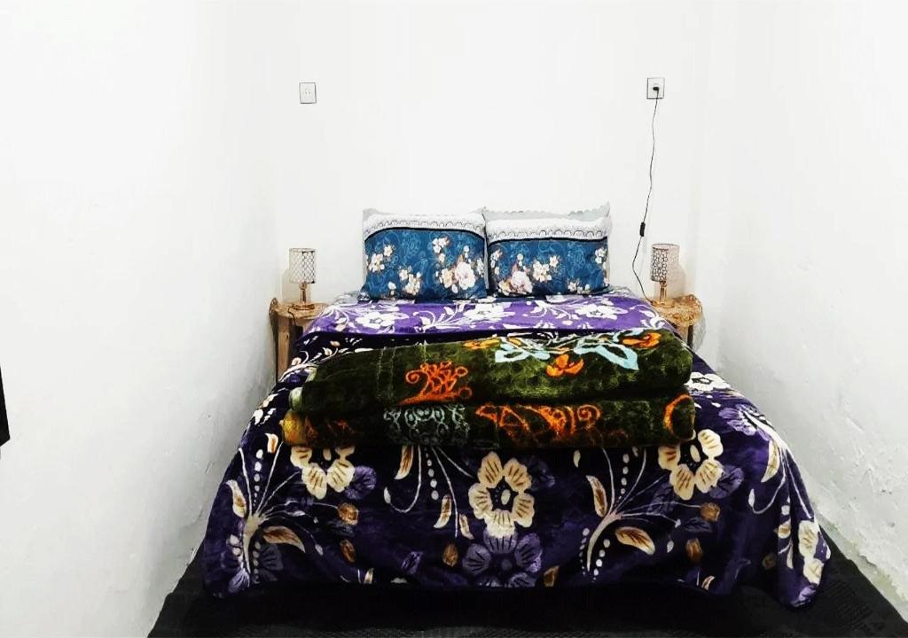 a bedroom with a bed with a colorful blanket at 1A private room in a shared house for surfers in Safi