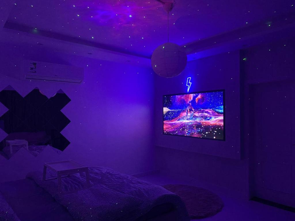 Habitación púrpura con cama y TV en Lovely Suite en Yeda