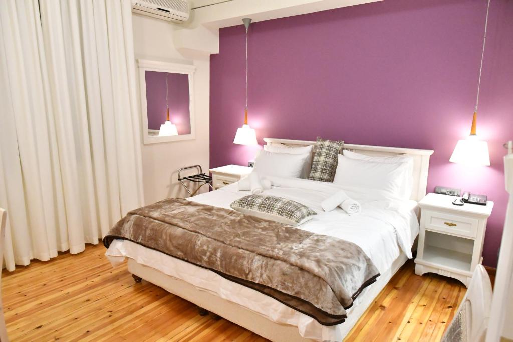 a bedroom with a large bed with a purple wall at Porto Nafplio in Nafplio
