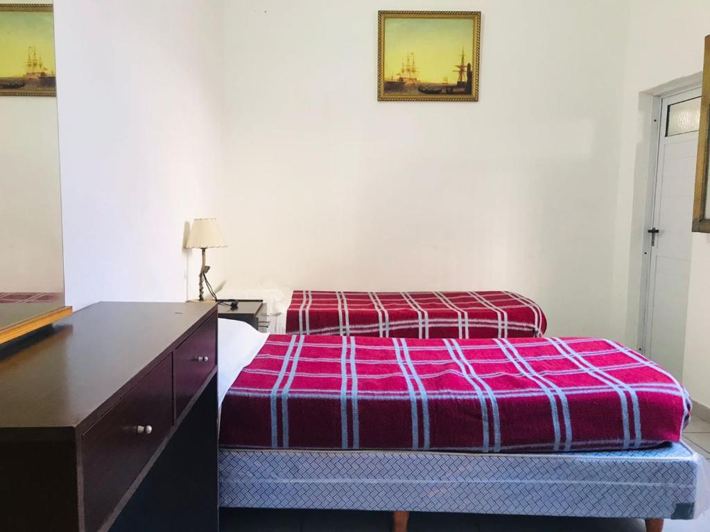 HOTEL PIAMONTE في بوينس آيرس: غرفة نوم مع سرير وخزانة مع بطانية أرجوانية