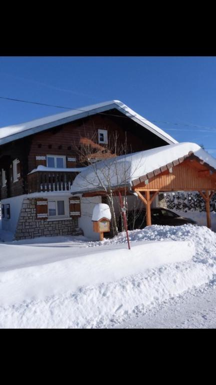 une maison avec un toit enneigé dans la neige dans l'établissement Charmant T2 proches centre village, aux Rousses