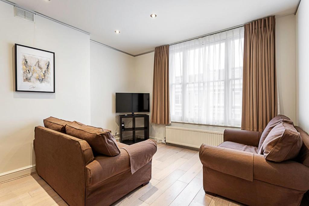 a living room with two chairs and a television at Cosy Kensington Two Bedroom Flat in London
