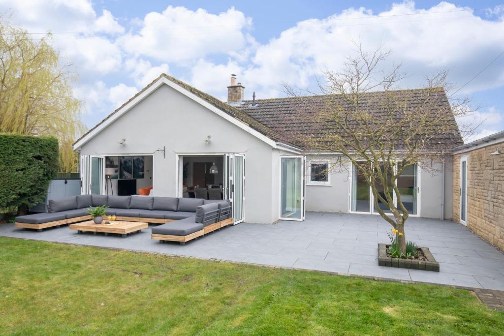 a white house with a patio and a tree at Magnificent 3-Bedroom Home with Swim Spa in Cheltenham