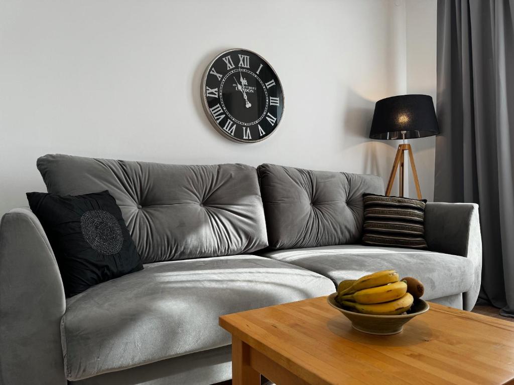 a living room with a couch and a clock on the wall at Koliber in Karwia