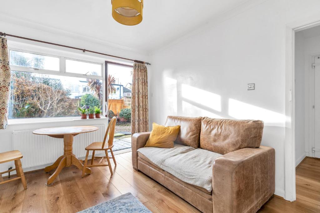 ein Wohnzimmer mit einem Sofa und einem Tisch in der Unterkunft Sunny 2BD London Maisonette with Garden for 3 in London