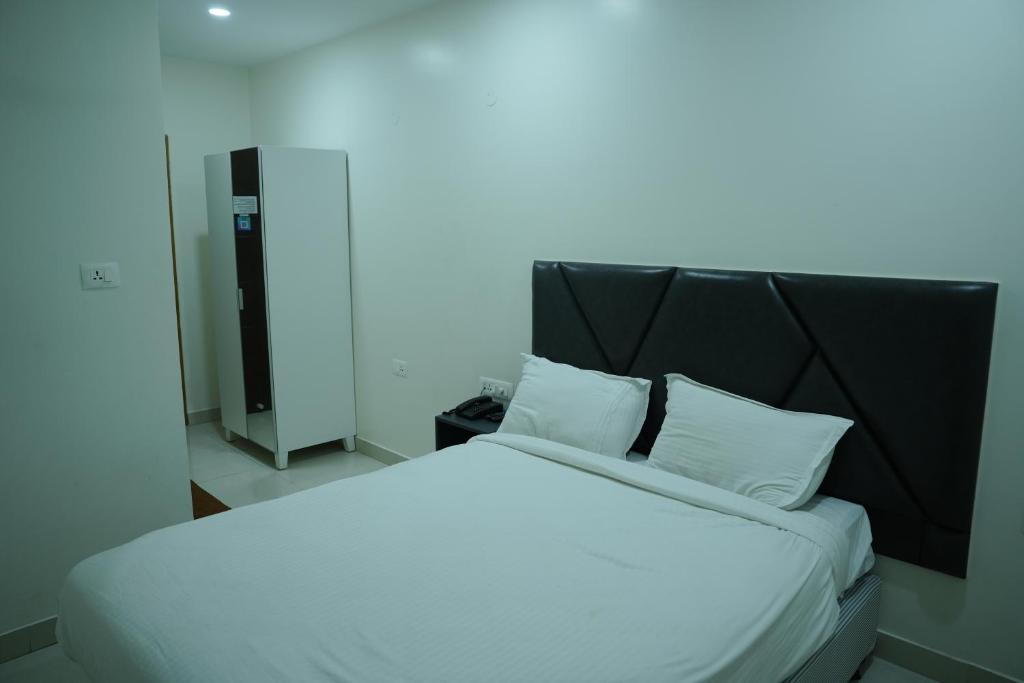 een wit bed met een zwart hoofdeinde en witte kussens bij 12 degree comforts in Bangalore