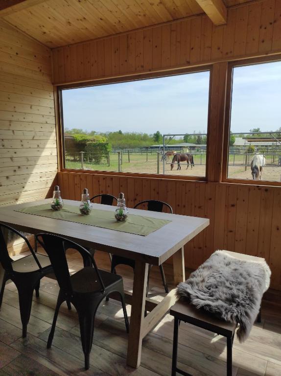 uma sala de jantar com uma mesa e duas cadeiras e um pasto para cavalos em Bosquey Ranch B&B em Alice Castello