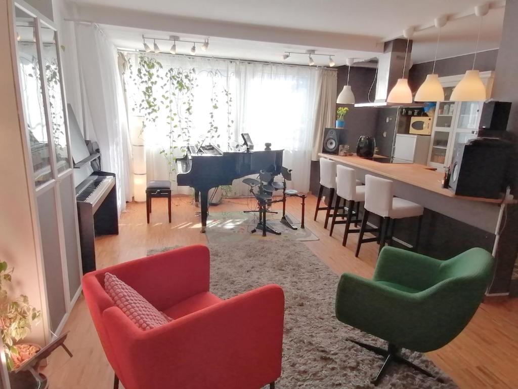 ein Wohnzimmer mit roten und grünen Stühlen und einem Klavier in der Unterkunft Lovely central flat with grand piano, family friendly in Berlin