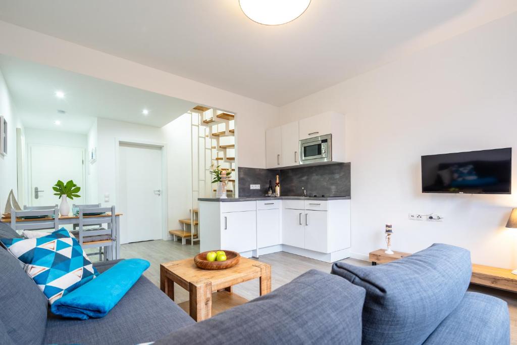 a living room with a blue couch and a kitchen at Ferienwohnung am Bug für 7 Gäste - Entspannung pur! #BugOase in Dranske