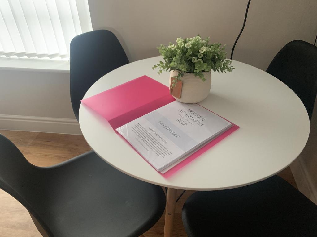 a white table with a book and a vase of flowers on it at Modern Spacious 2 Bed Apartment **Free WIFI & Parking** in Goodmayes