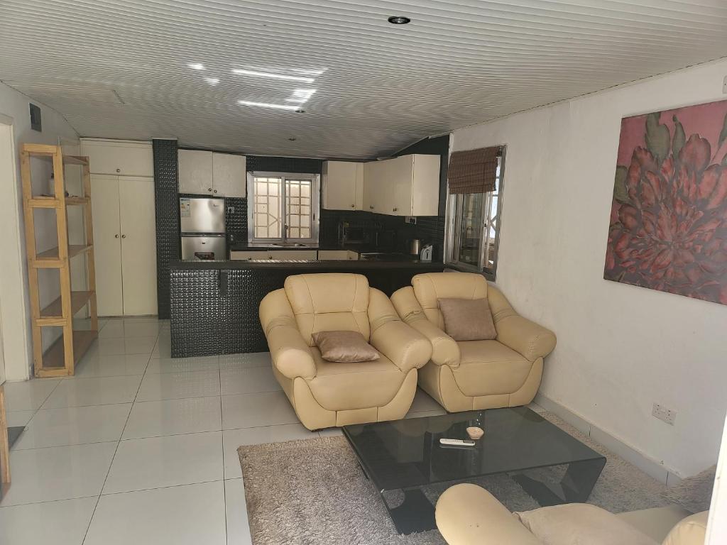 a living room with two chairs and a table at Cozy 2 Bedroom Bungalow. in Freetown