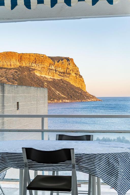 une table et des chaises sur un balcon avec vue sur l'océan dans l'établissement Le Super Bestouan par Dodo à Cassis, à Cassis