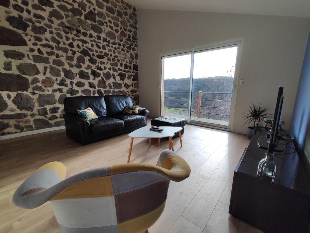 un soggiorno con divano e parete in pietra di Maison vigneronne climatisée a Polignac