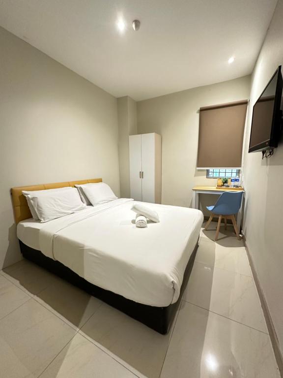 Schlafzimmer mit einem großen weißen Bett und einem Schreibtisch in der Unterkunft Swing & Pillows PJ Sunway Mentari formerly known as Swan Cottage Hotel in Petaling Jaya