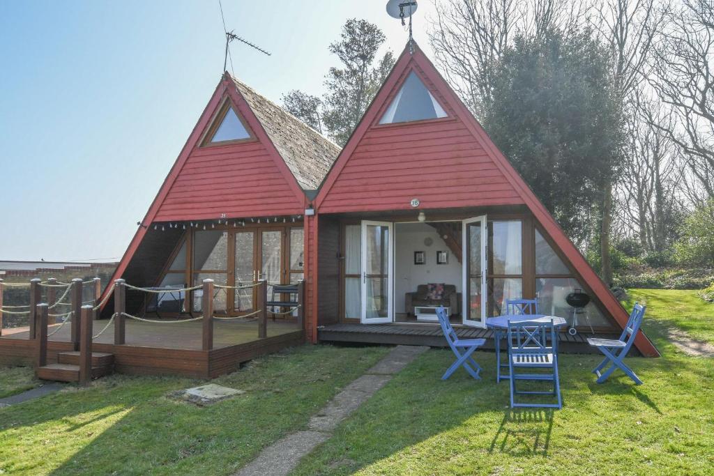 a large red roofed house with a table and chairs at Chalet Thirtysix in Deal