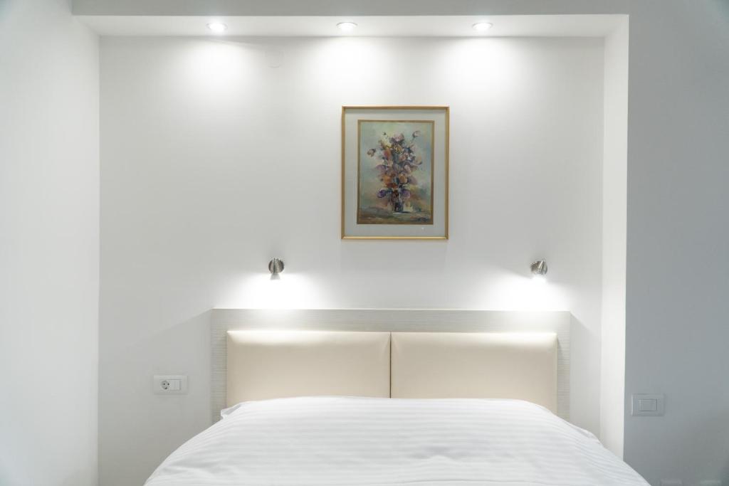 a bedroom with a white bed with lights on it at Sienna Apartments in Skopje