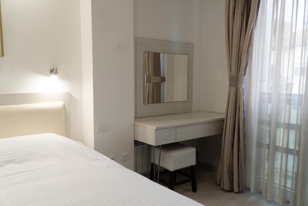 a white bedroom with a mirror and a bed at Sienna Apartments in Skopje