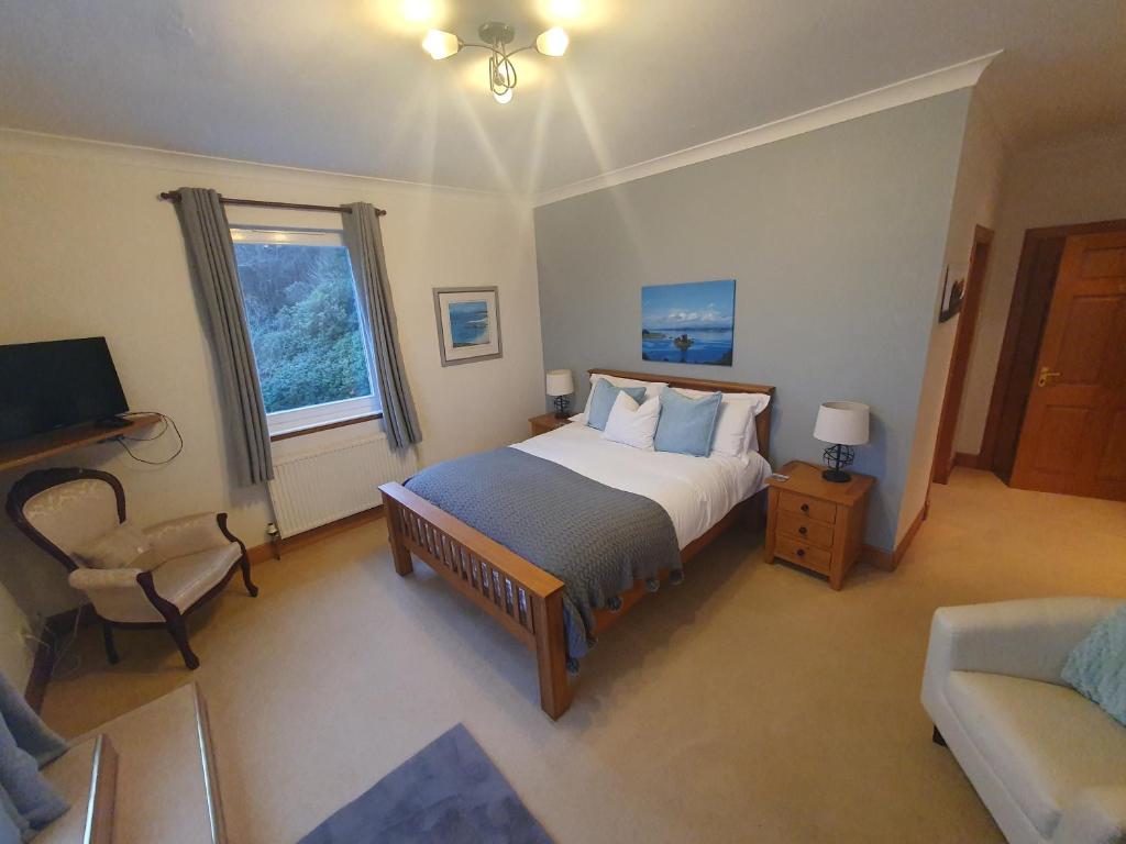 een slaapkamer met een bed, een stoel en een televisie bij Appin Bay View in Appin