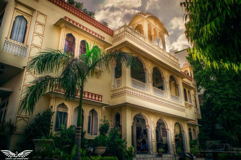 un grande edificio con una palma di fronte di Krishna Palace - A Heritage Hotel a Jaipur