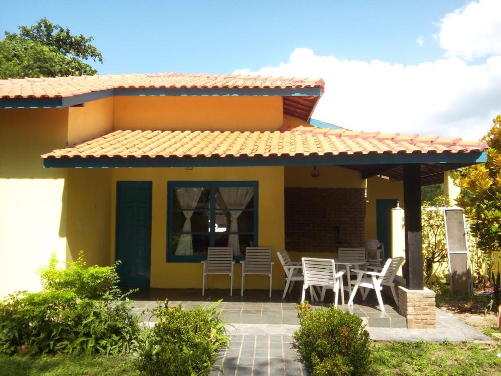 a small yellow house with chairs and a patio at Ilha , Vera Cruz, Cacha Pregos um lugar lindo e tranquilo ! in Vera Cruz de Itaparica