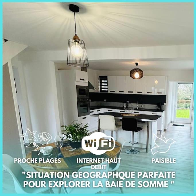 une cuisine blanche avec une table et des chaises dans l'établissement Le Gîte de La Baie A Velo, à Nouvion-en-Ponthieu