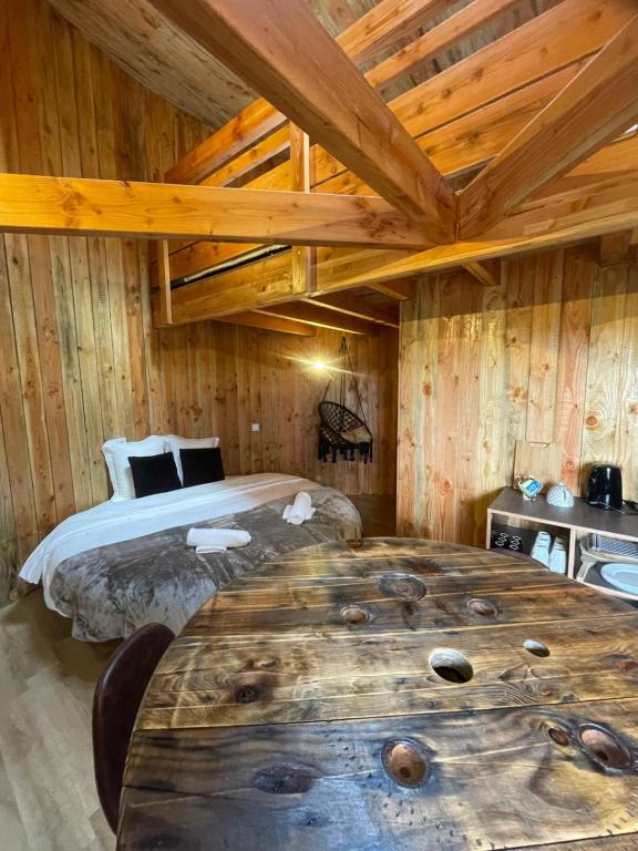 Un dormitorio con una cama y una gran mesa de madera. en La Cabane Tonneau - Les Pieds dans le Pré, en Les Landes-Génusson