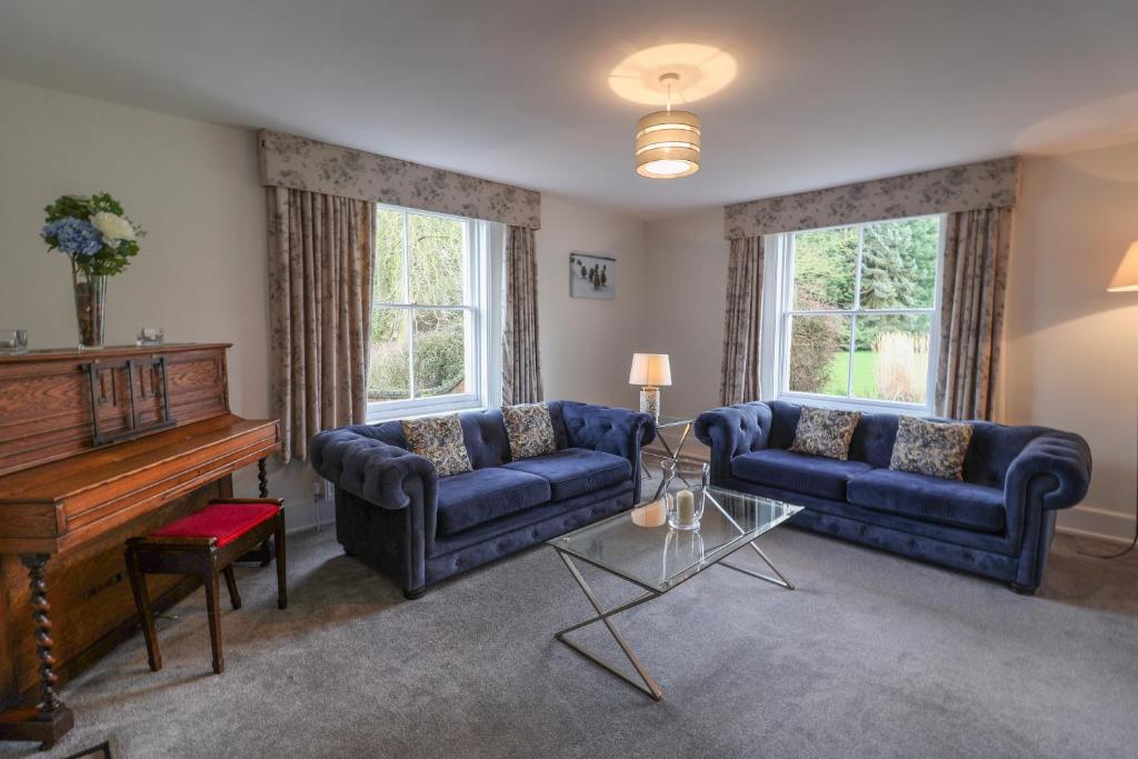 a living room with blue couches and a piano at Bedingfield House, nr Debenham in Debenham