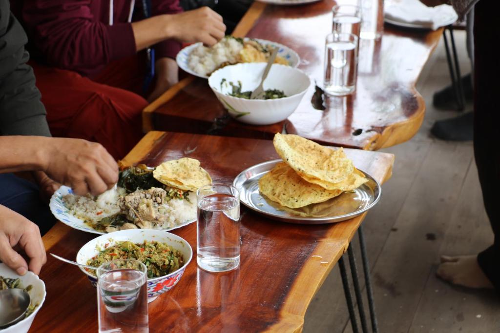 a group of people sitting at a table with plates of food at Tsering's Homestay Oyan in Pāsighāt